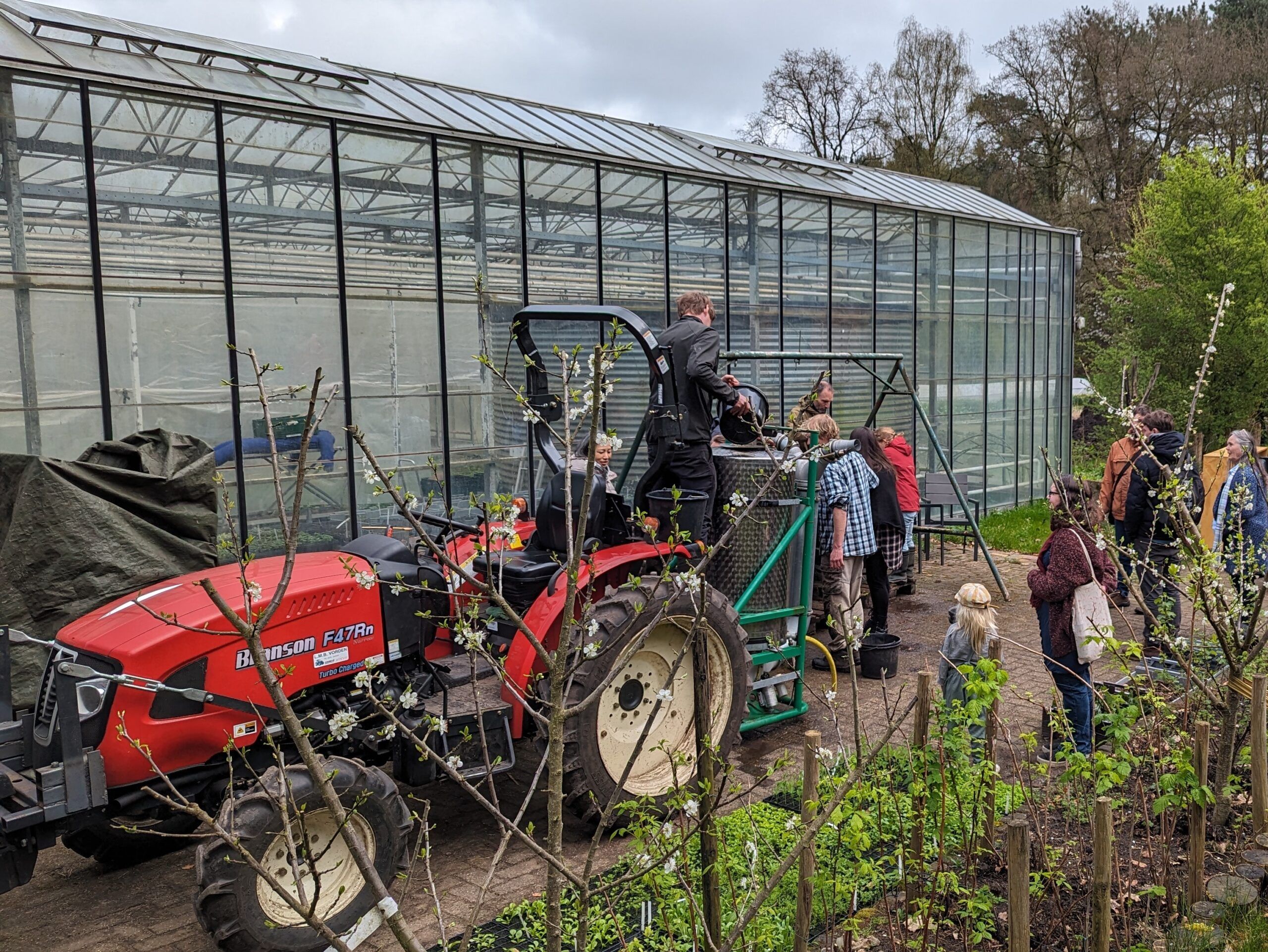 tracktor en mensen voor de kas