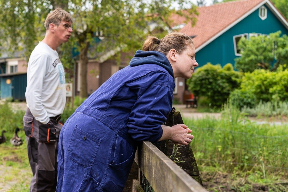 twee mensen hangen over een hek