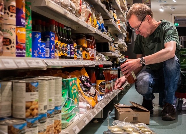 medewerker die de schappen in de winkel aan het bijvullen is